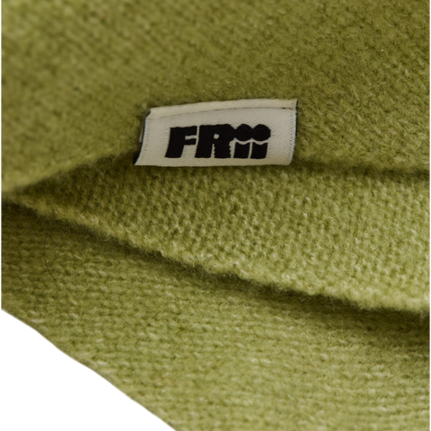 Close up of a light green scarf or baby bib with a frii label on it