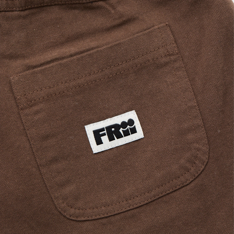Close up of a brown pant pocket with a frii logo on a brown background