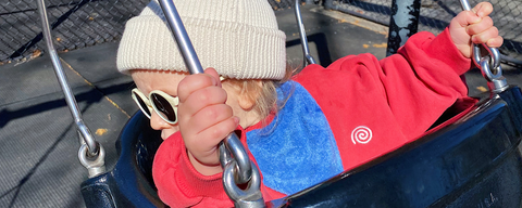 Child in a red and blue jacket on a swing set