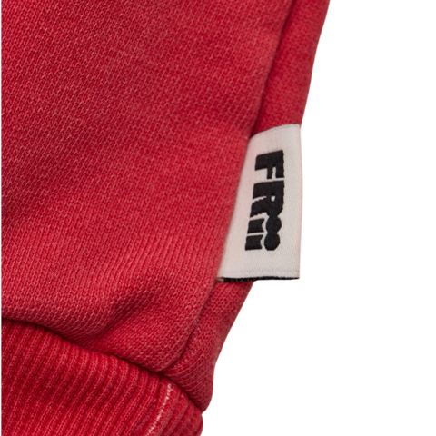 Close up of a red sweater with a frii brand label on a white background