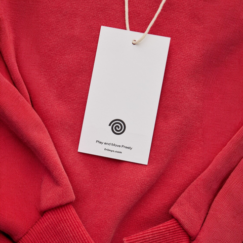 Red sweater with a white tag featuring a swirl logo and text on a matching red background